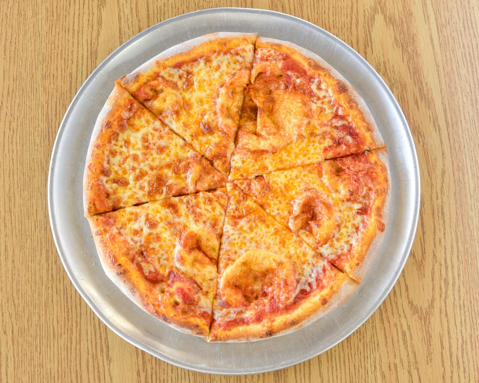 A whole cheese pizza, cut into eight slices, on a metal tray on a wooden table.