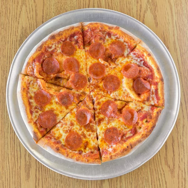 A whole pepperoni pizza, sliced into eight pieces, on a metal tray atop a wooden table.